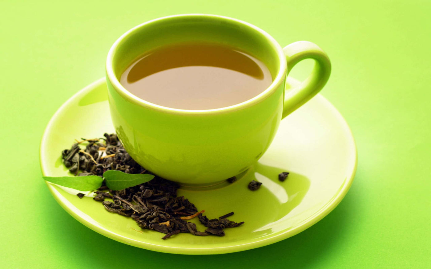 kratom tea in a cup|Tea in a light green cup with dried herbs on the saucer