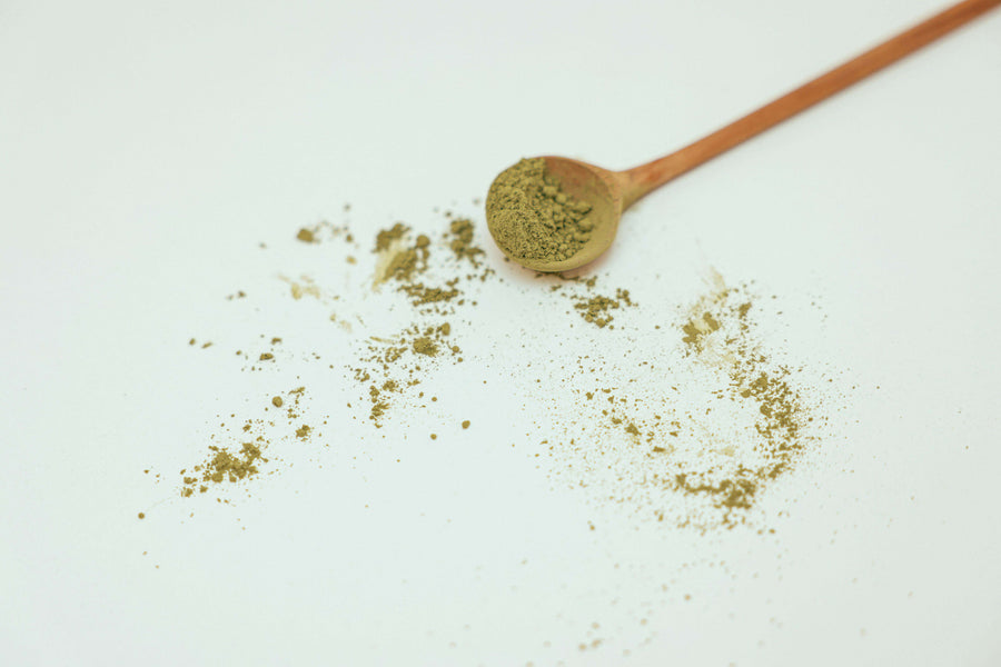 Red Bali kratom powder with wooden spoon|glass jar of reddish-brown powder